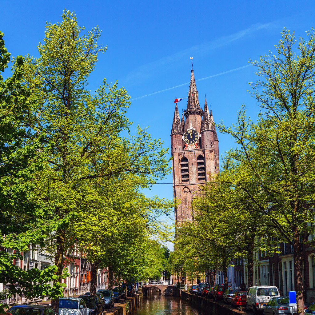 Oude Kerk van Delft boven de gracht en groene bomen