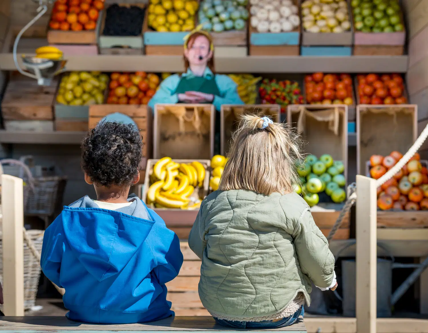 Kinderen kijken naar fruit en groente bij de boerderijwinkel