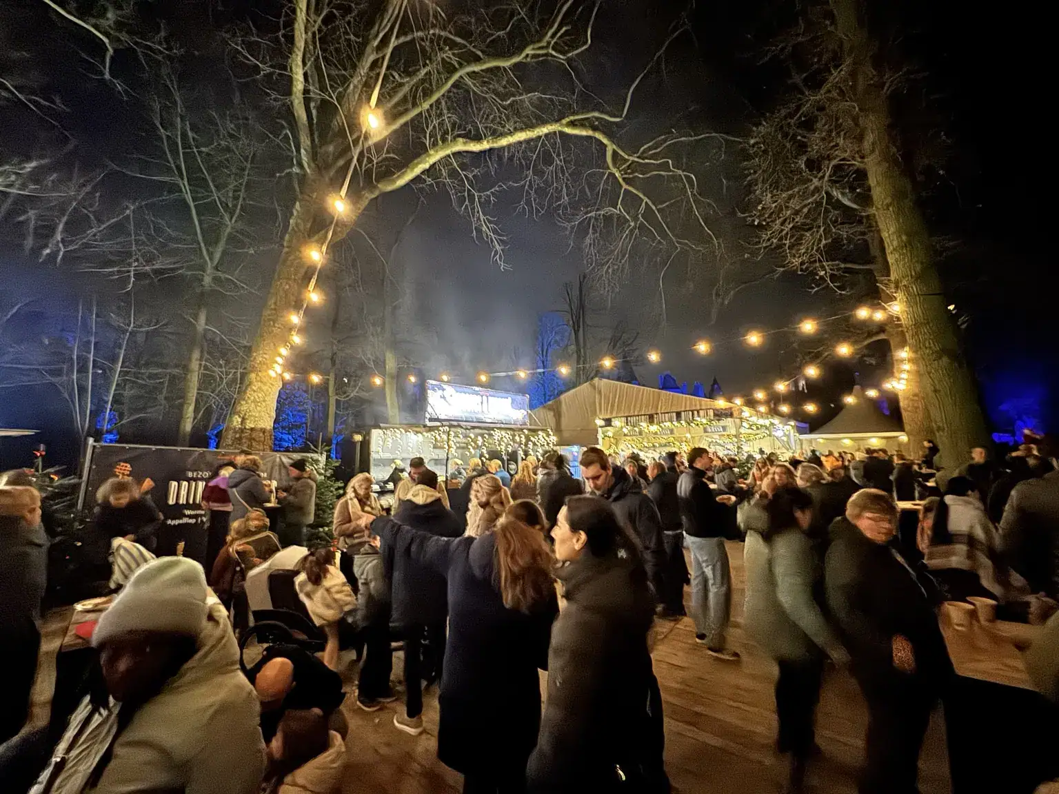 Verlicht winterterras met foodtrucks en bezoekers halverwege de route